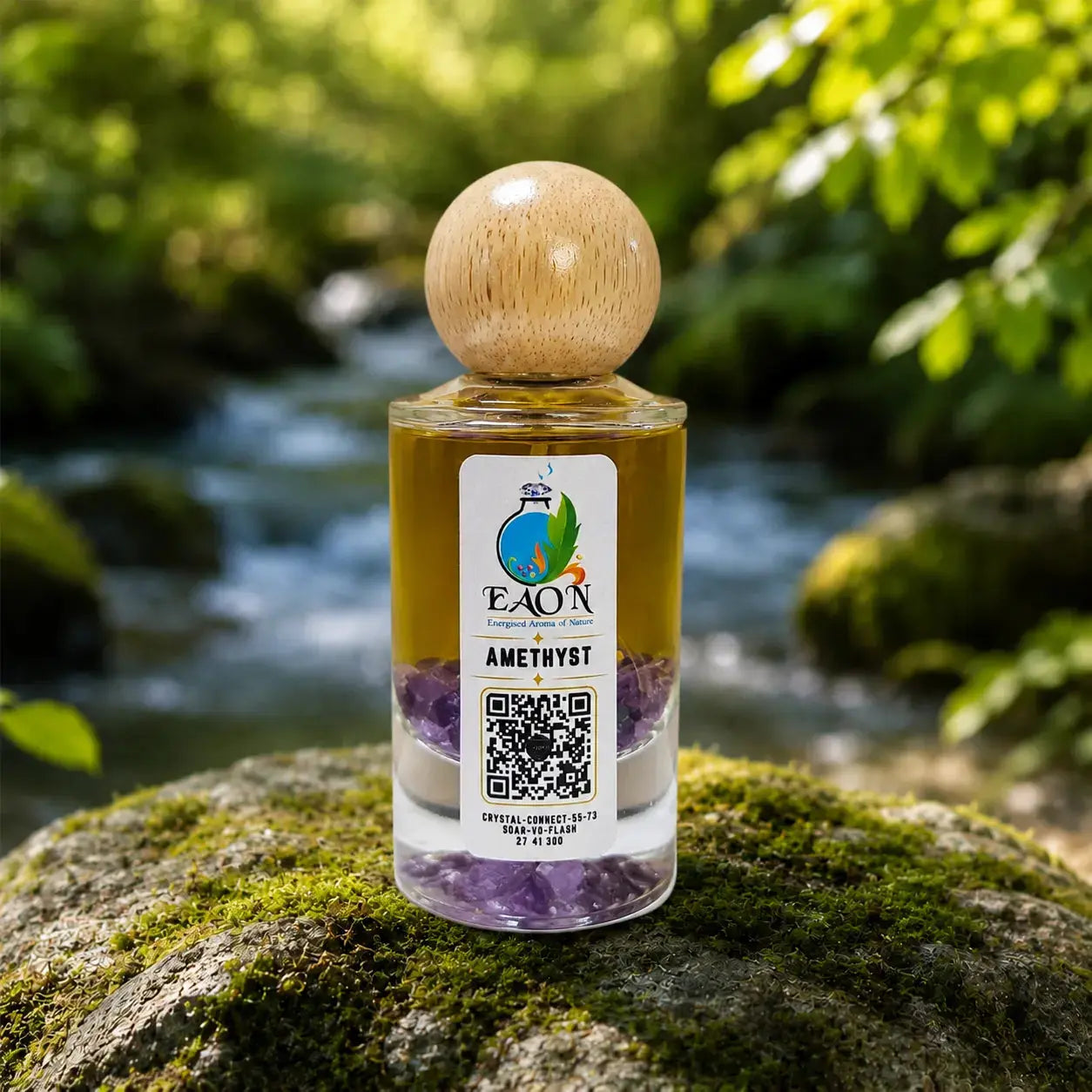 Bottle of EAON Amethyst essential oil with a wooden cap on a mossy rock by a stream.