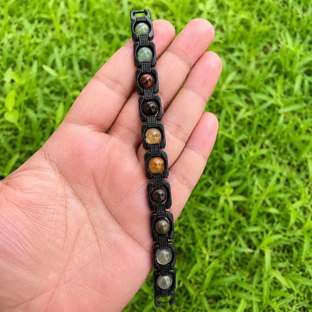 money magnet metal frame bracelet worn in a hand with a grass background 