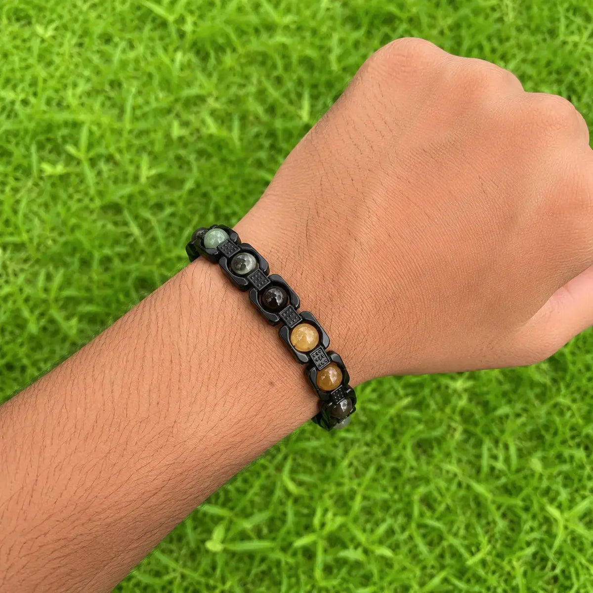 money magnet metal frame bracelet worn in a hand with a grass background 